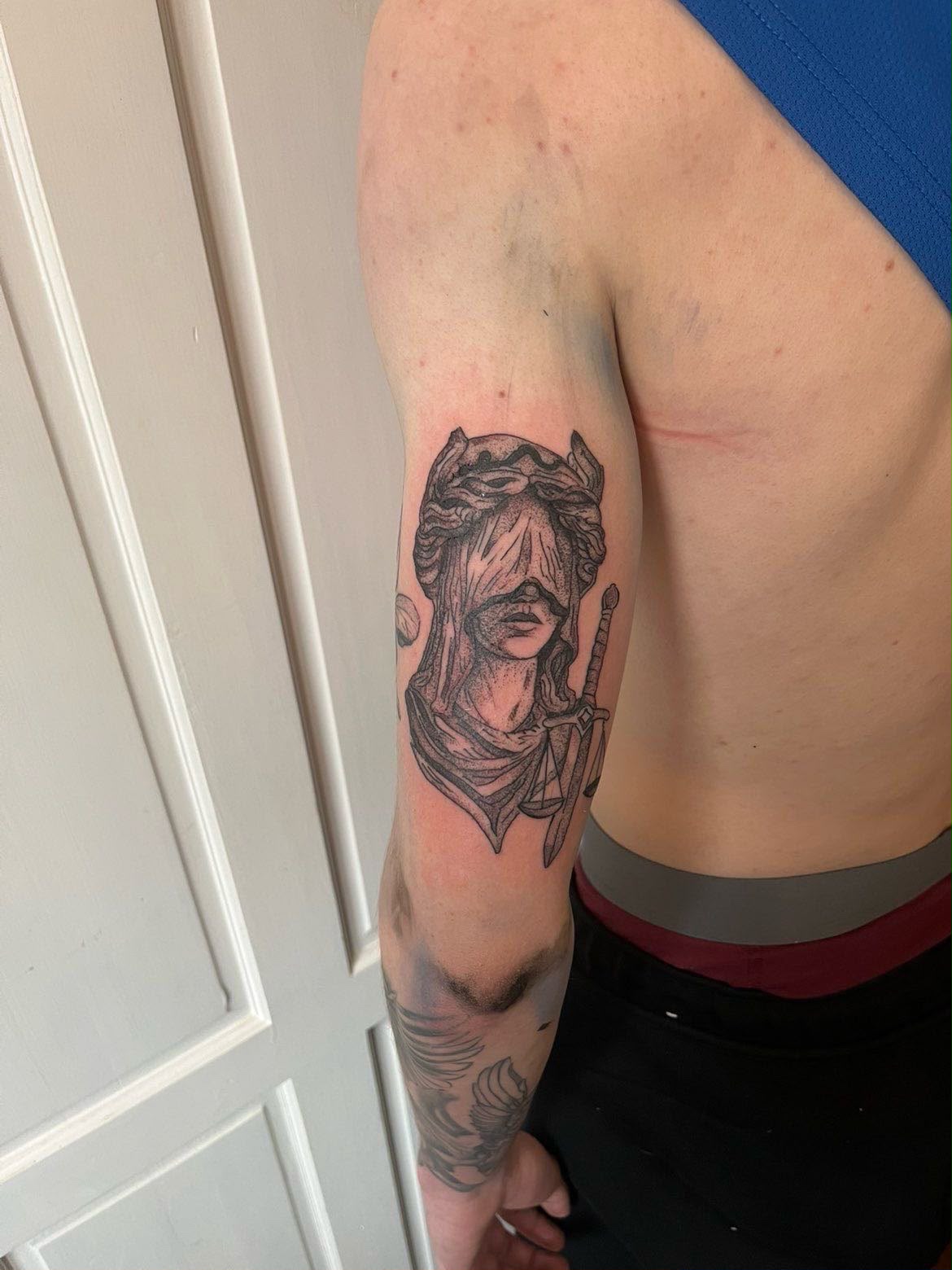 Blackwork Lady Justice upper-arm tattoo